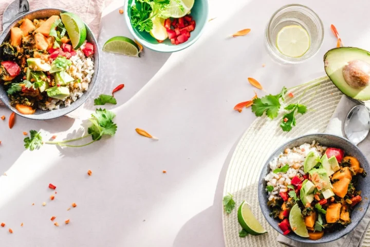 Twee kommen met groente, avocado en peulvruchten van bovenaf: afvallen tips in de praktijk