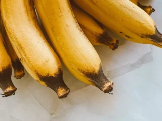 Rijpe gele bananen op een marmeren ondergrond; calorieën banaan: ongeveer 110 kcal per stuk