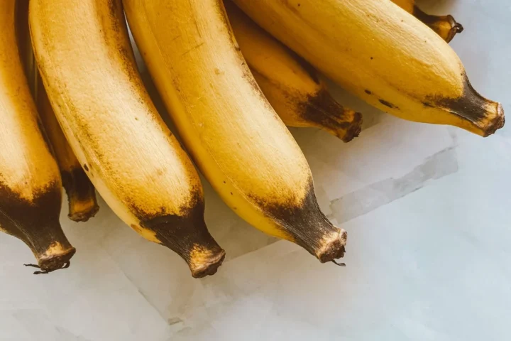 Rijpe gele bananen op een marmeren ondergrond; calorieën banaan: ongeveer 110 kcal per stuk