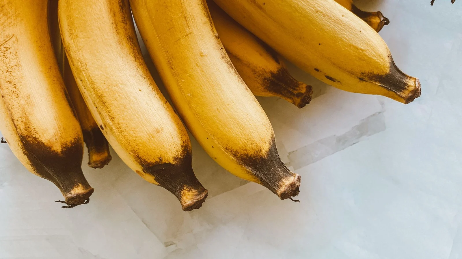 Rijpe gele bananen op een marmeren ondergrond; calorieën banaan: ongeveer 110 kcal per stuk