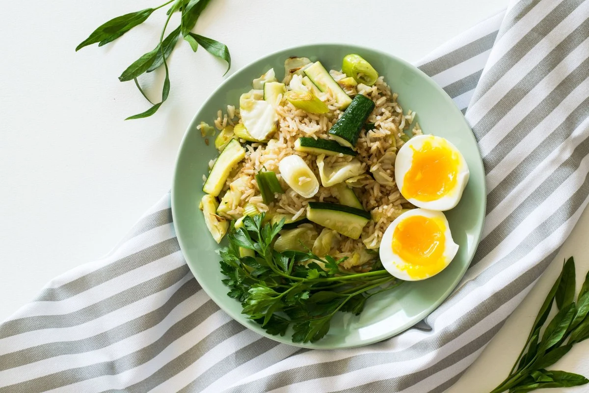 Kom met rijst, courgette, groene blaadjes en een zachtgekookt ei