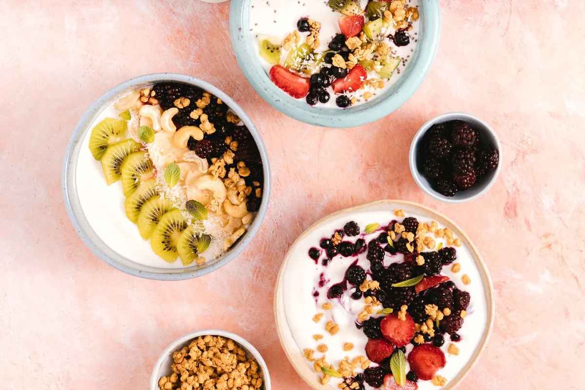 Kommen yoghurt met kiwi, bramen, blauwe bessen, banaan en noten van bovenaf gezien