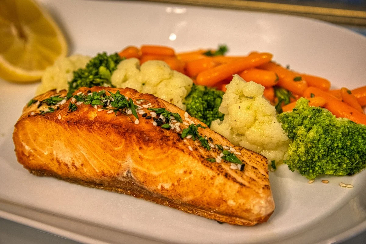Gebakken zalmfilet met broccoli, bloemkool en wortel op een wit bord, een gezond avondeten