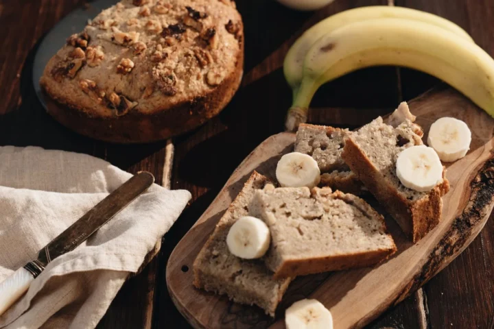 Gezond bananenbrood in plakken met verse banaan en plakjes banaan op een houten plank