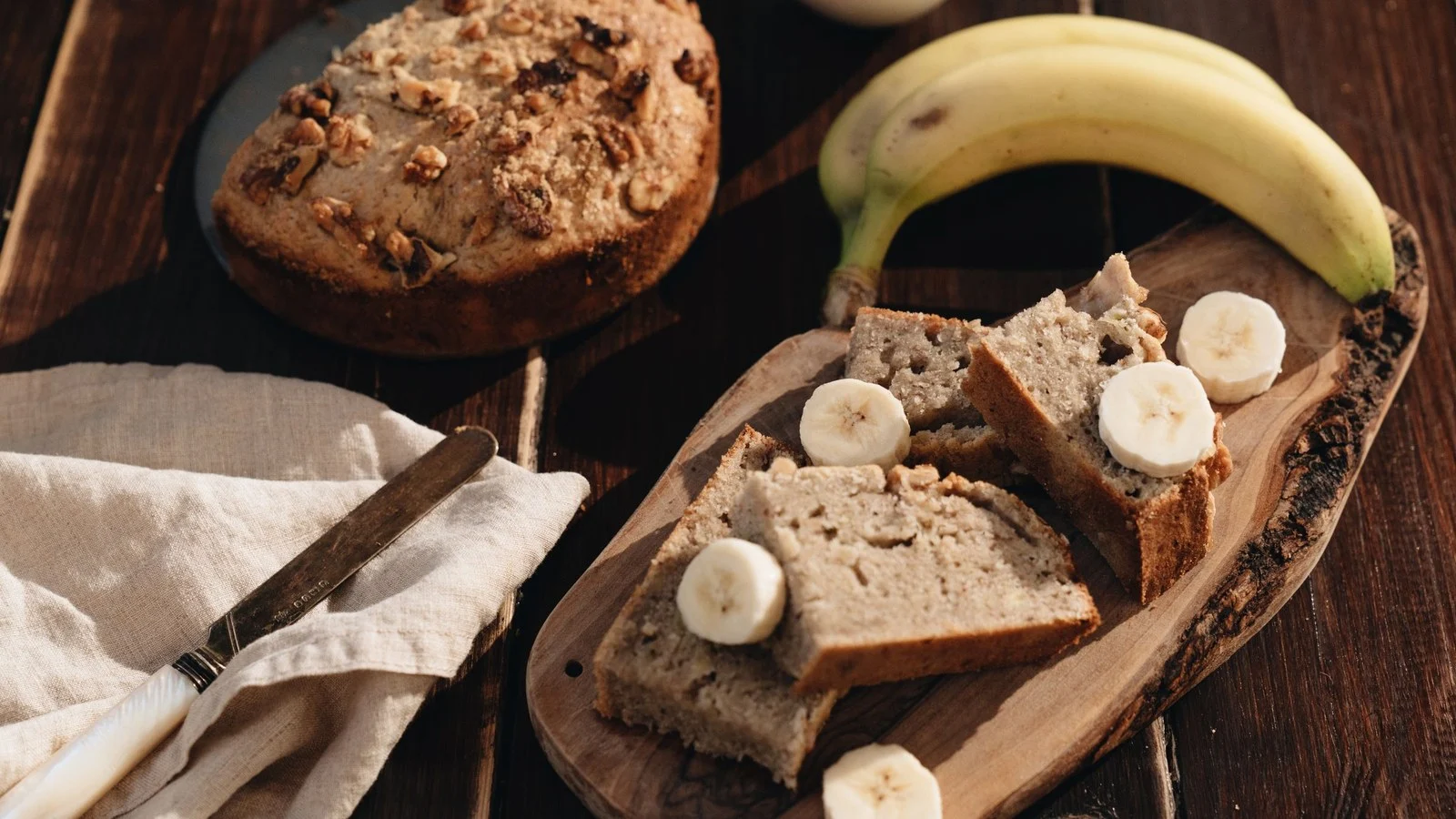 Gezond bananenbrood in plakken met verse banaan en plakjes banaan op een houten plank