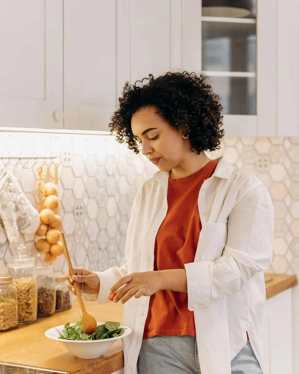 Vrouw maakt een verse salade in een lichte keuken