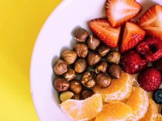 Kom met hazelnoten, aardbeien, blauwe bessen en partjes mandarijn als gezonde snacks