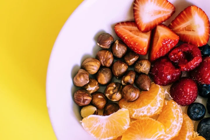 Kom met hazelnoten, aardbeien, blauwe bessen en partjes mandarijn als gezonde snacks